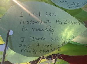A green paper leaf with handwritten message reading: I think that researching Parkinson's is amazing! I learnt a lot and it was really clearly explained.